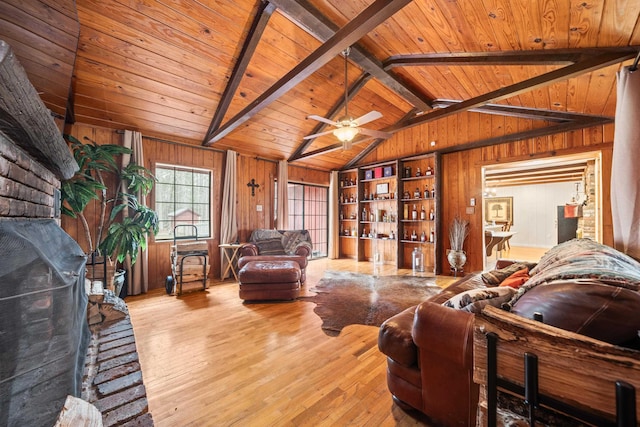 living room with wood ceiling, lofted ceiling with beams, light wood-type flooring, wooden walls, and ceiling fan