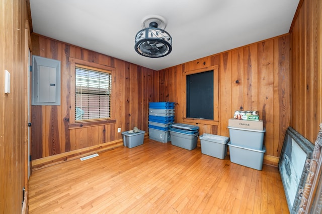 miscellaneous room featuring electric panel, light hardwood / wood-style floors, and wood walls