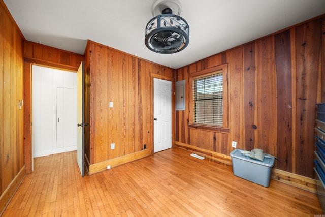 interior space featuring light hardwood / wood-style flooring, electric panel, and wood walls