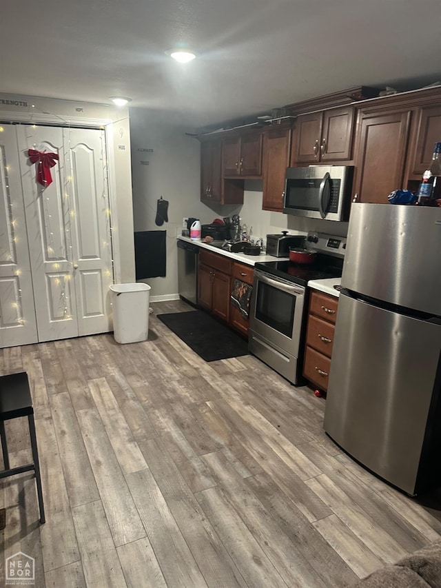 kitchen featuring dark brown cabinets, light hardwood / wood-style flooring, and stainless steel appliances