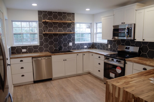 kitchen featuring appliances with stainless steel finishes, sink, white cabinets, and butcher block countertops