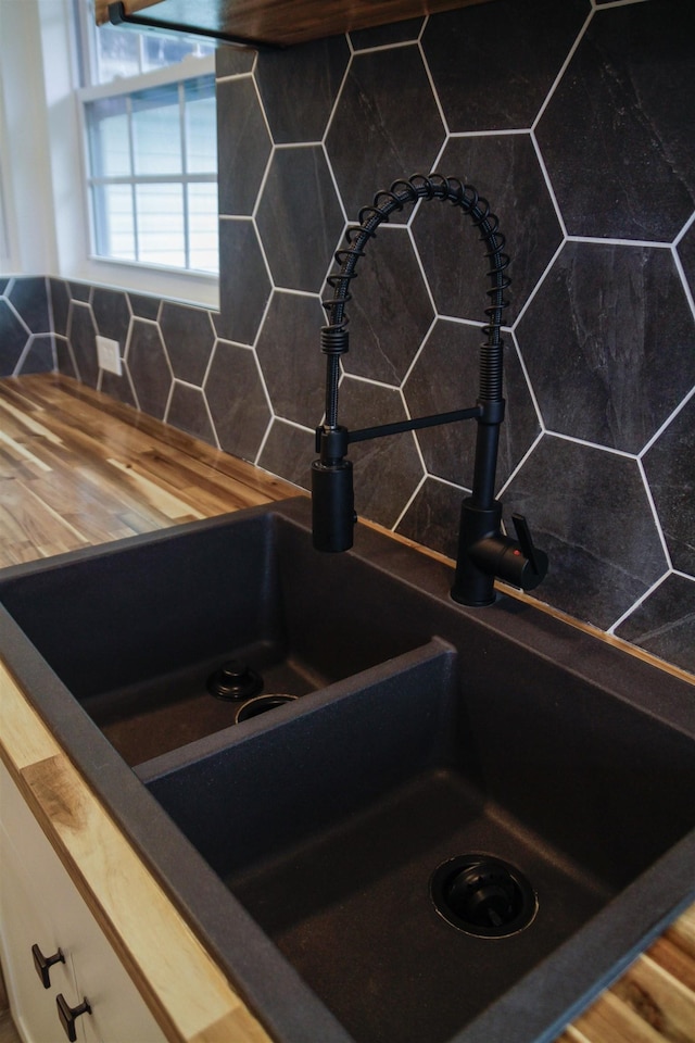 details featuring tasteful backsplash, butcher block counters, and sink