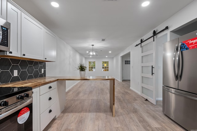 kitchen with decorative light fixtures, stainless steel appliances, wooden counters, and white cabinets