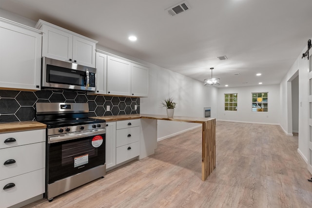 kitchen featuring white cabinetry, hanging light fixtures, stainless steel appliances, tasteful backsplash, and wood counters