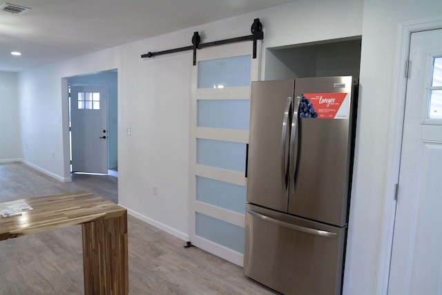 kitchen featuring stainless steel fridge, light hardwood / wood-style floors, and a barn door