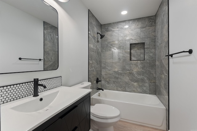 full bathroom with toilet, vanity, tiled shower / bath combo, hardwood / wood-style flooring, and backsplash