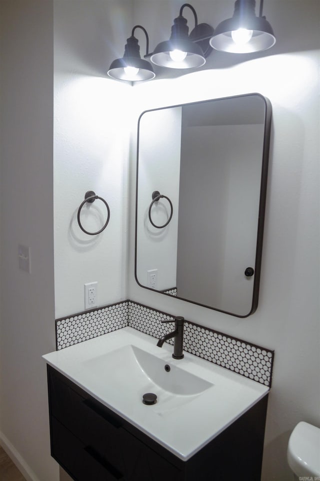 bathroom with vanity, toilet, and decorative backsplash