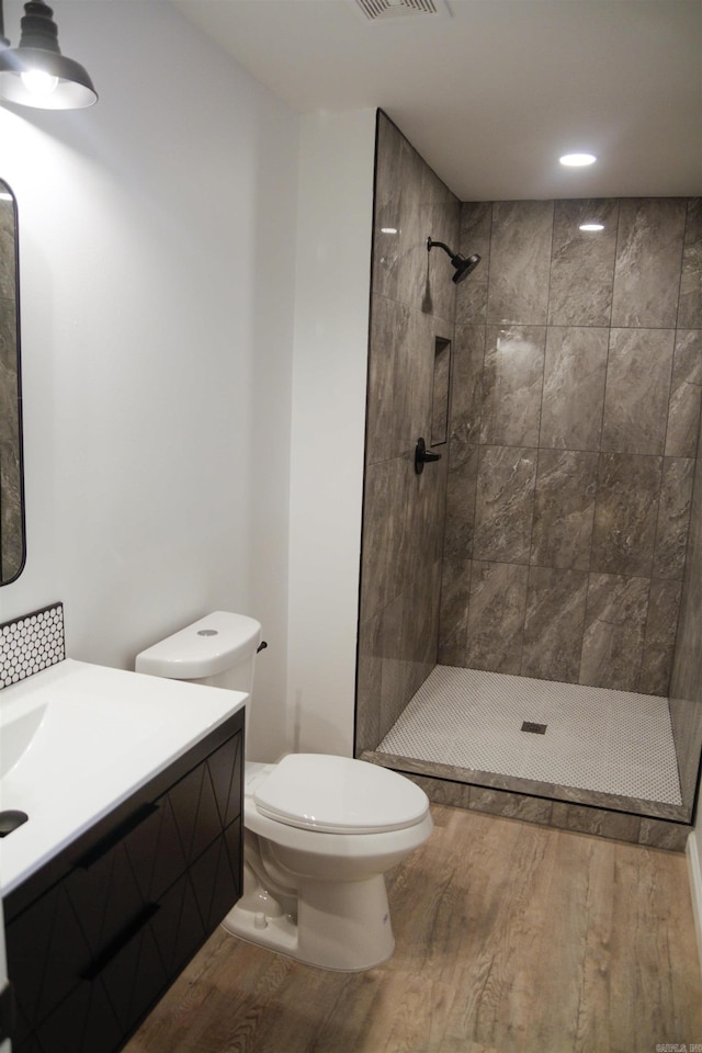 bathroom with vanity, hardwood / wood-style floors, toilet, and tiled shower