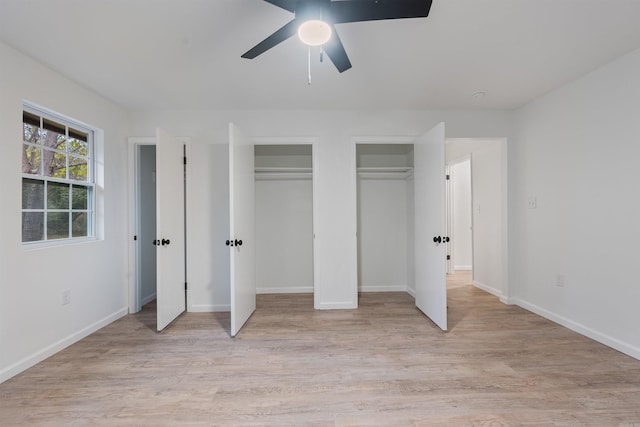 unfurnished bedroom featuring two closets, ceiling fan, and light hardwood / wood-style flooring