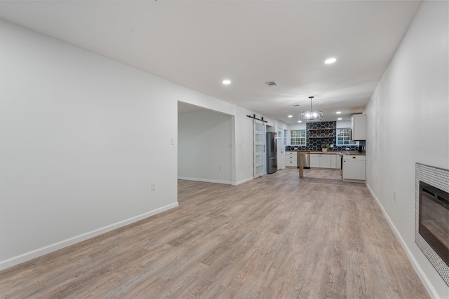 unfurnished living room featuring light hardwood / wood-style flooring and a barn door