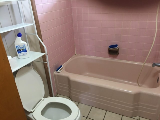 bathroom featuring toilet, tiled shower / bath combo, and tile patterned flooring