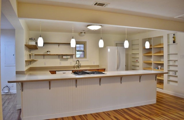 kitchen featuring pendant lighting, a kitchen breakfast bar, stainless steel gas stovetop, and white refrigerator