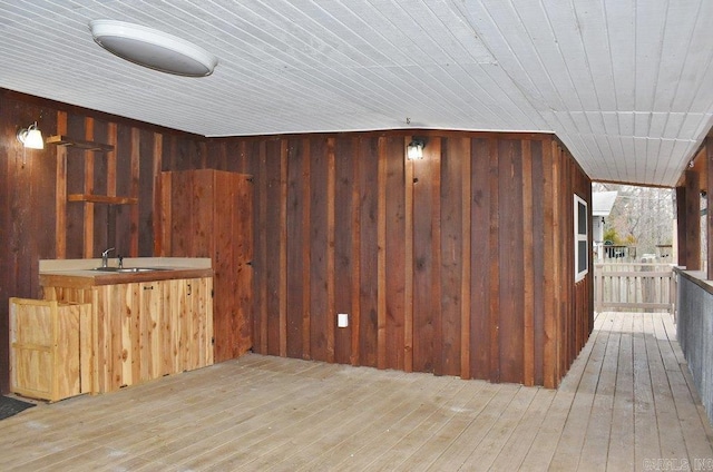 bar with sink, light hardwood / wood-style flooring, wooden ceiling, and wood walls