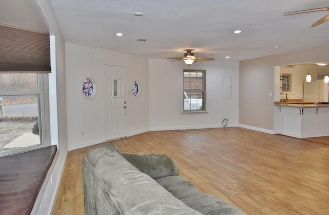 living room with electric panel, ceiling fan, and light hardwood / wood-style floors