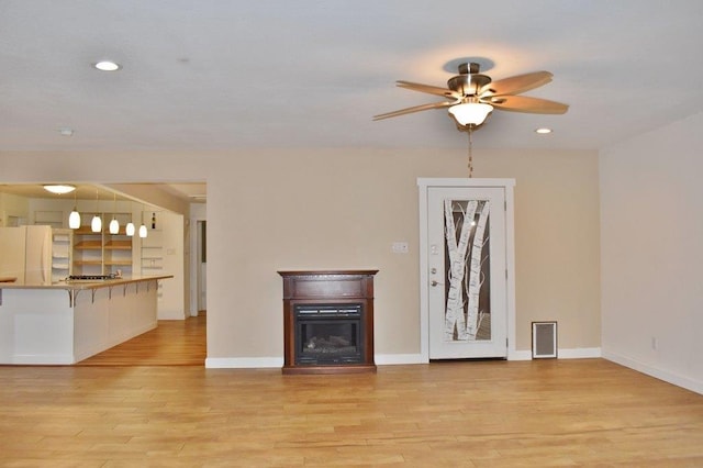 unfurnished living room with ceiling fan and light wood-type flooring