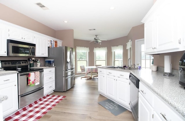 kitchen featuring ceiling fan, white cabinetry, stainless steel appliances, kitchen peninsula, and light wood-type flooring