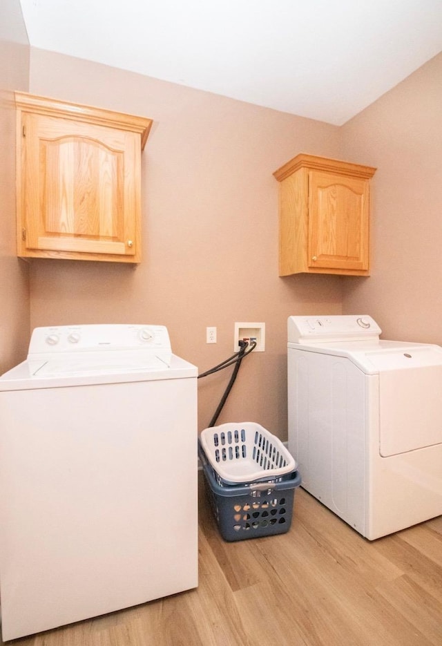 washroom with cabinets, washer and clothes dryer, and light hardwood / wood-style floors