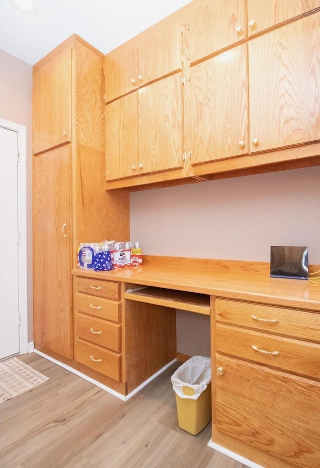 office space featuring built in desk and light hardwood / wood-style flooring