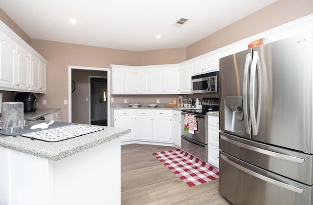 kitchen featuring stainless steel appliances, light hardwood / wood-style flooring, and white cabinets