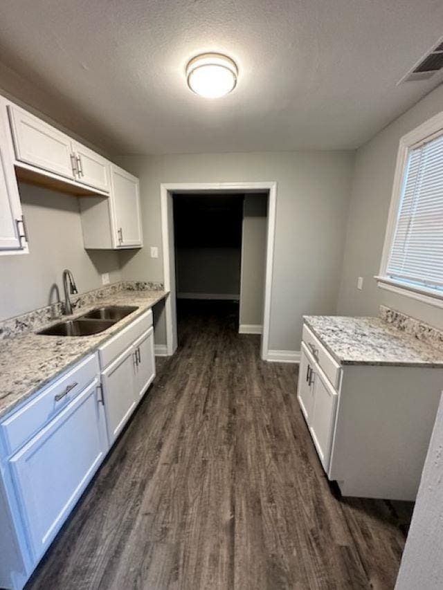 kitchen with sink, white cabinets, light stone countertops, dark wood-type flooring, and a textured ceiling