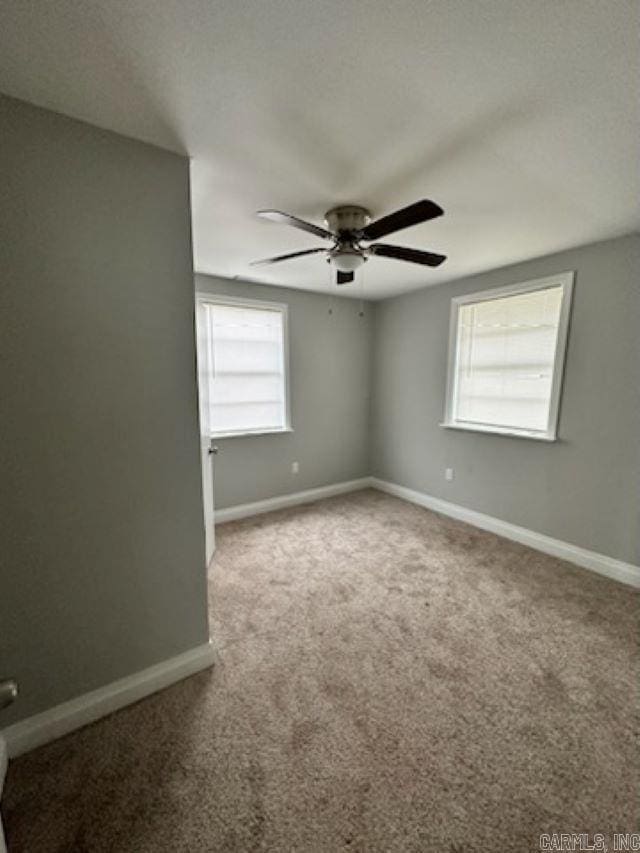 carpeted spare room with ceiling fan