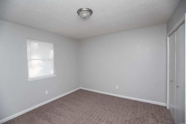 carpeted empty room featuring a textured ceiling