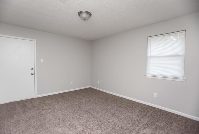 carpeted empty room featuring a textured ceiling