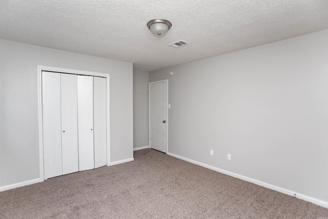 unfurnished bedroom featuring carpet flooring, a textured ceiling, and a closet