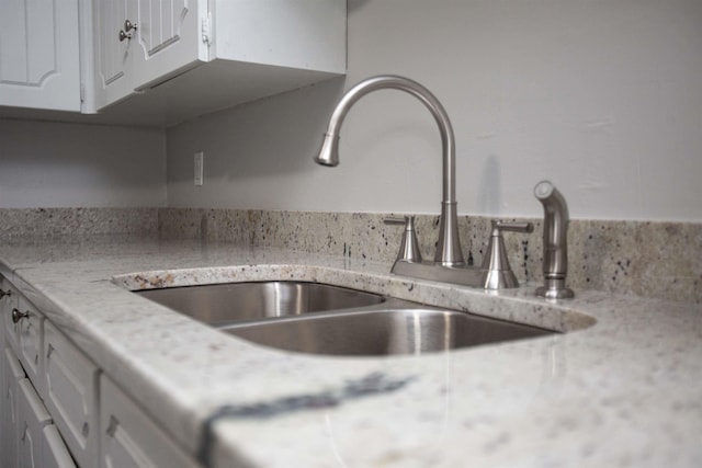 details with light stone counters, sink, and white cabinets