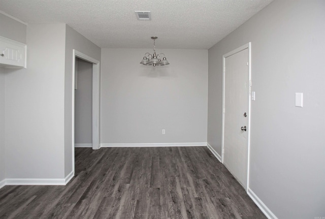 unfurnished dining area with dark wood-type flooring, a textured ceiling, and a notable chandelier