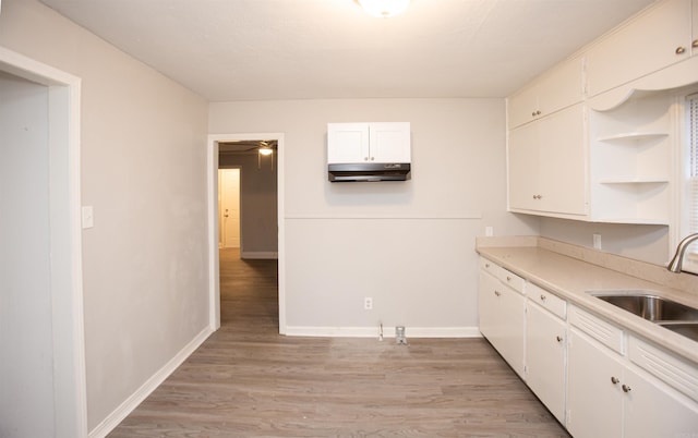 kitchen with sink, white cabinets, and light wood-type flooring