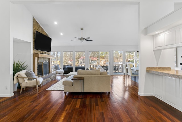 living room featuring plenty of natural light, dark wood-type flooring, high vaulted ceiling, and a fireplace