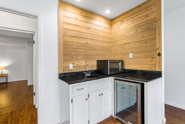 bar with wine cooler, white cabinetry, dark wood-type flooring, and sink