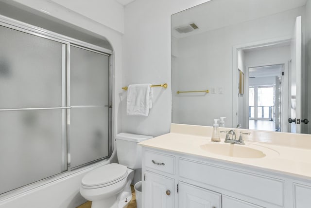 full bathroom with toilet, vanity, and bath / shower combo with glass door