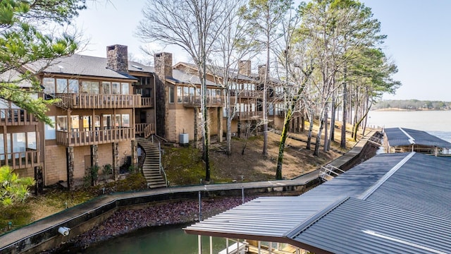 back of property with cooling unit, a balcony, and a water view