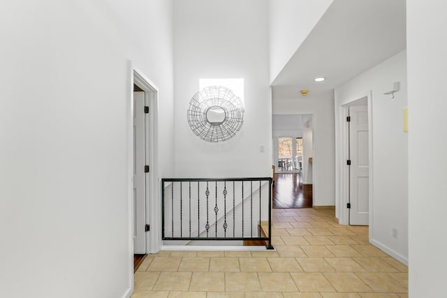 hallway with a towering ceiling and light tile patterned flooring