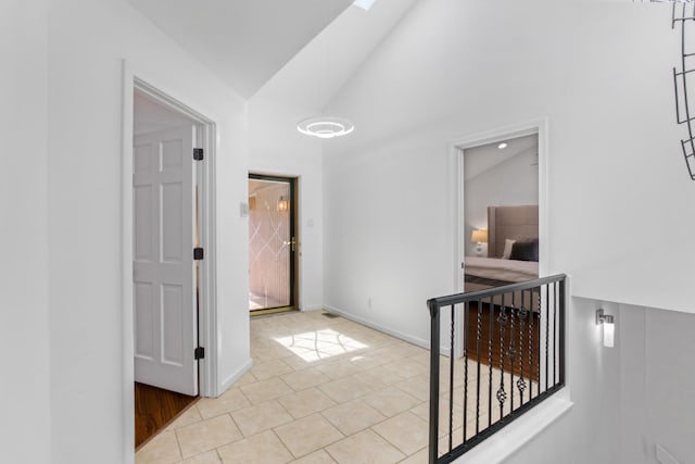 hall featuring light tile patterned floors and high vaulted ceiling