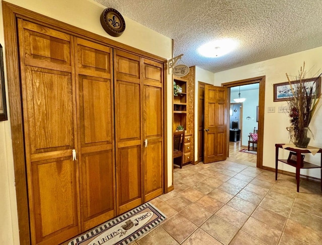 hall with light tile patterned floors and a textured ceiling