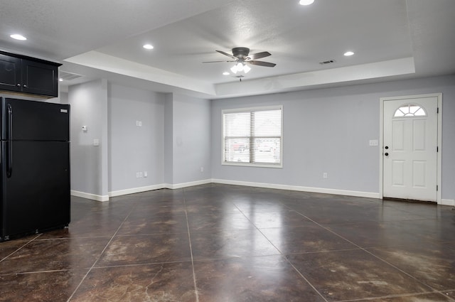 unfurnished living room with a raised ceiling and ceiling fan