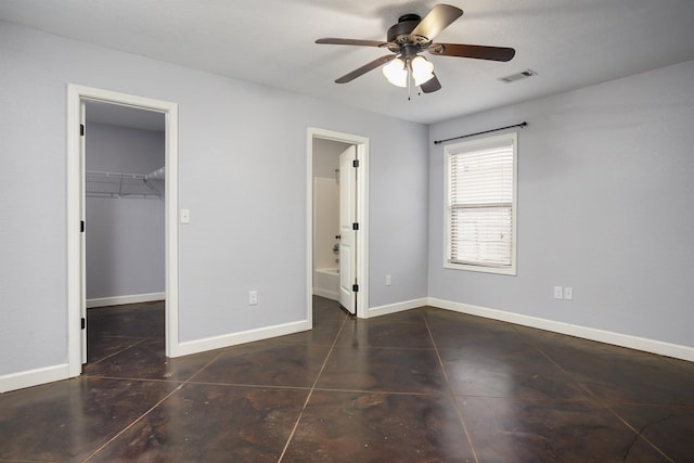 unfurnished bedroom with ensuite bath, a walk in closet, a closet, and ceiling fan