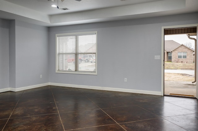 tiled empty room with a raised ceiling