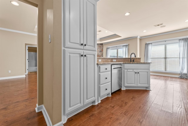 kitchen featuring ornamental molding, stainless steel dishwasher, kitchen peninsula, and white cabinets