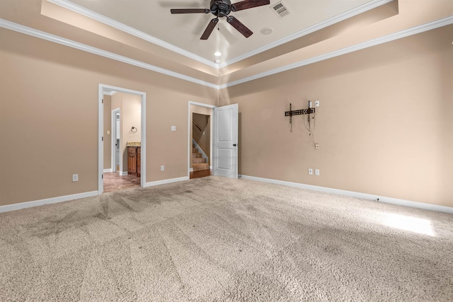 unfurnished bedroom with connected bathroom, a tray ceiling, ornamental molding, and carpet