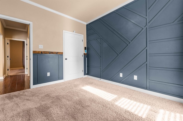 spare room with ornamental molding and dark colored carpet