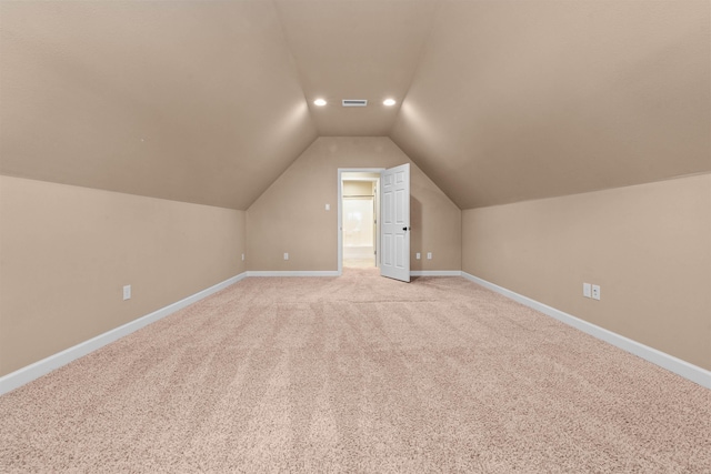 bonus room with vaulted ceiling and light colored carpet