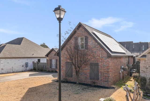 rear view of house featuring brick siding, fence, and a barn