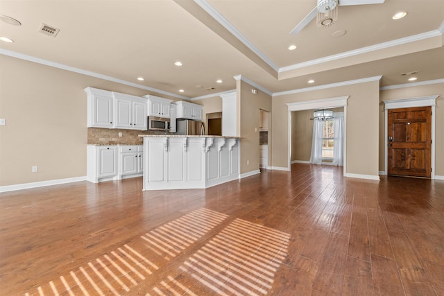 unfurnished living room featuring hardwood / wood-style flooring, ceiling fan, a tray ceiling, and crown molding