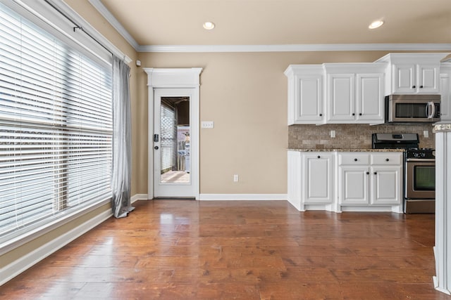 kitchen with white cabinetry, hardwood / wood-style floors, stainless steel appliances, tasteful backsplash, and ornamental molding