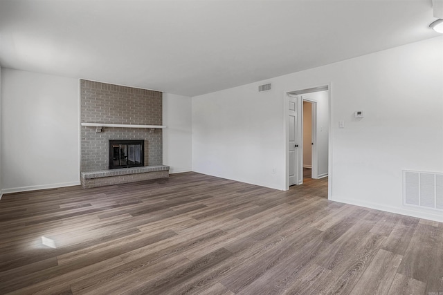 unfurnished living room with a brick fireplace and wood-type flooring