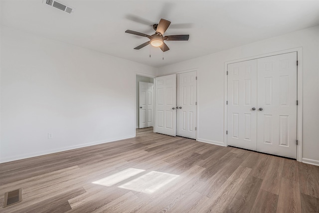 unfurnished bedroom featuring two closets, ceiling fan, and light hardwood / wood-style flooring